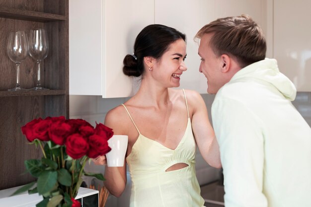 Romantic couple at home celebrating valentines day with bouquet of beautiful red roses