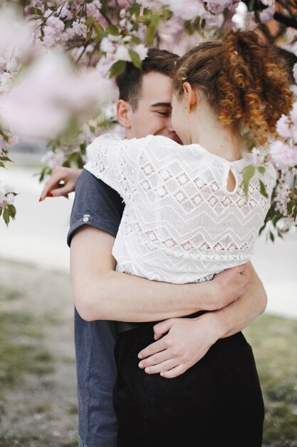 Romantic couple hugs under the blossom spring tree