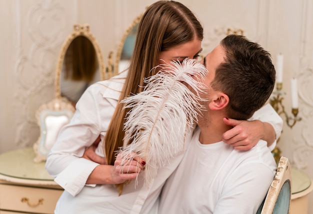 romantic couple kissing and covering mouths with feather