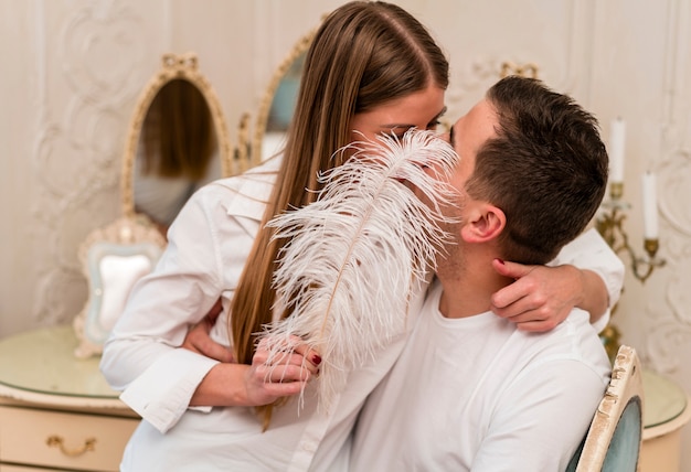Романтическая пара целует и прикрывает рот пером