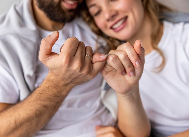 Romantic couple locking pinkies on the sofa at home