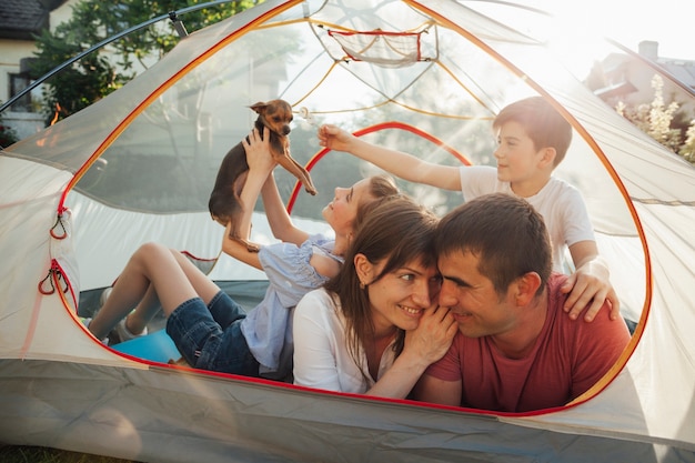 Romantic couple looking at each other while their kids playing with dog in tent