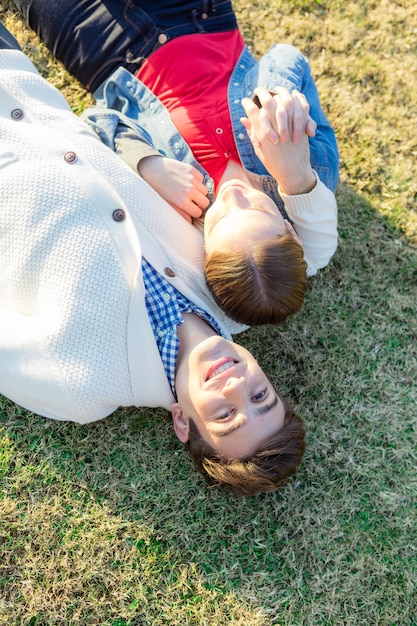 ロマンチックなカップルは、芝生の上に横たわっていると、自分の手で遊んで