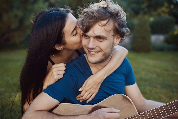 Free photo romantic couple sitting on the grass in the garden