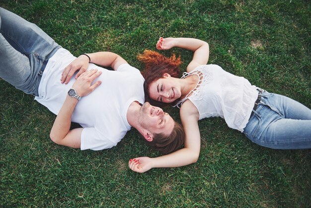 A romantic couple of young people lying on the grass in the park.