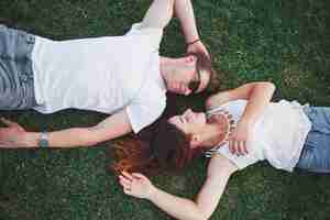 Free photo romantic couple of young people lying on grass in park.