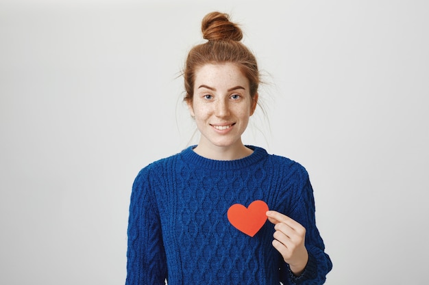 Romantic cute redhead girl holding heart sign