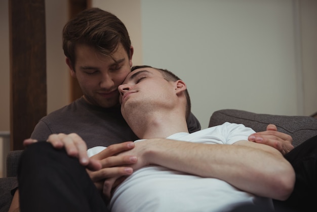 Romantic gay couple embracing on sofa in living room