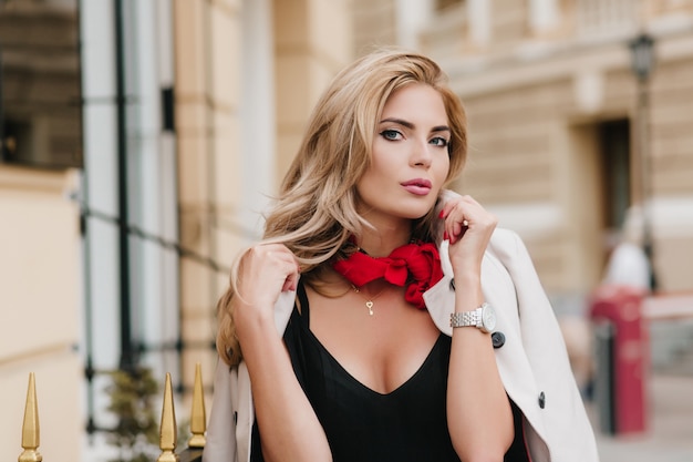 Romantic girl wears golden pendant looking with interest while posing after walk around town