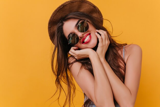 Romantic girl with cute smile posing in sparkle sunglasses while standing 