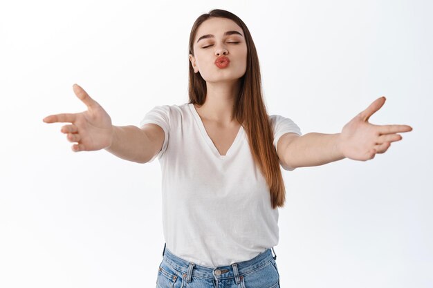 Romantic girlfriend reach for kiss, woman stretch out hands to hug, hold or embrace someone, pucker lips for kissing, standing over white background