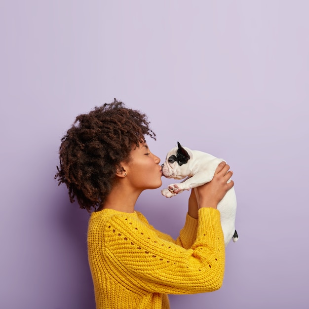 無料写真 ロマンチックな瞬間。巻き毛の黒い肌の雌犬の飼い主は愛らしいペットとのキスを楽しんでいます