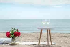 무료 사진 꽃과 바다로 샴페인 잔과 함께 낭만적 인 피크닉. 휴일의 개념.