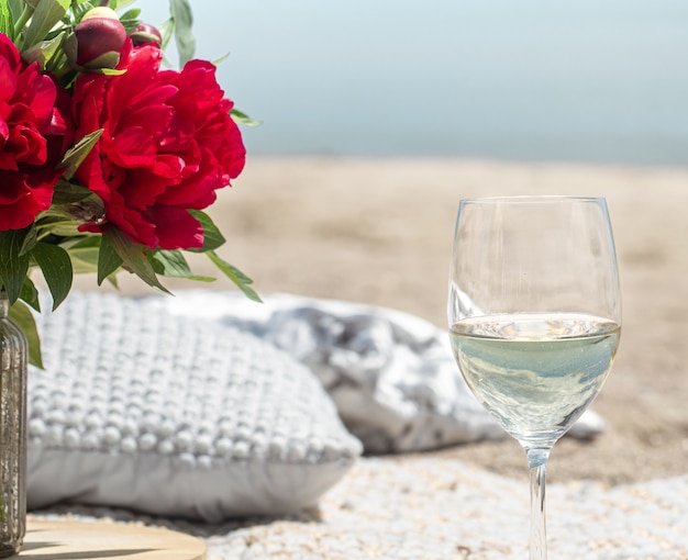Романтический пикник с цветами и бокалами шампанского на берегу моря. Концепция праздника.