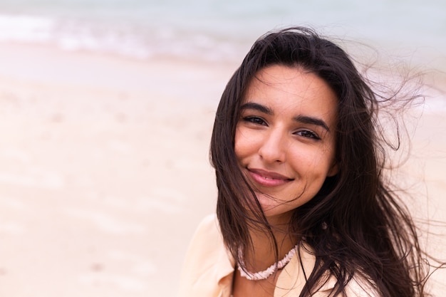 Romantic portrait of woman on beach at windy day, sunset warm light.