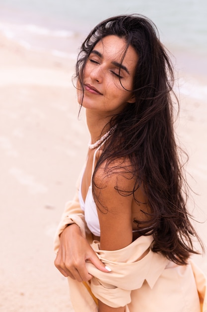 Romantic portrait of woman on beach at windy day, sunset warm light.