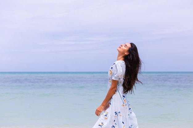 Free photo romantic portrait of woman in long blue dress on beach by sea at windy day