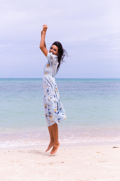 Романтический портрет женщины в длинном синем платье на пляже у моря в ветреный день