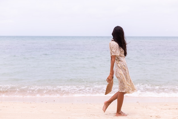 Романтический портрет женщины в длинном платье на пляже в ветреный пасмурный день.