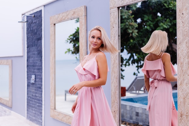 Free photo romantic portrait of woman in pink evening cute dress hold wild flowers outside luxury tropical villa beautiful female with bouquet