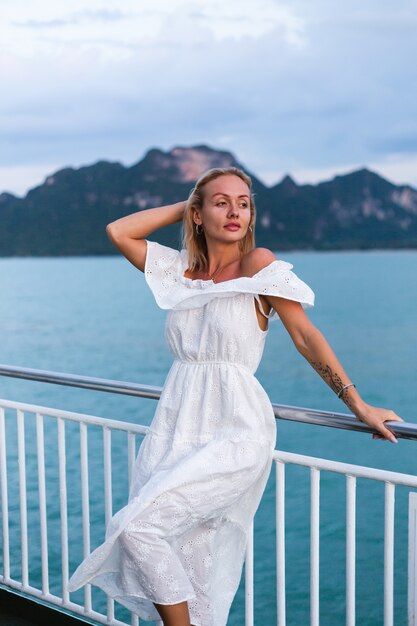 Romantic portrait of woman in white dress sailing on large boat ferry