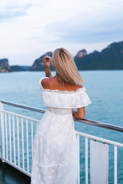 Romantic portrait of woman in white dress sailing on large boat ferry