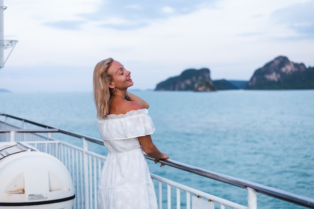 Romantic portrait of woman in white dress sailing on large boat ferry