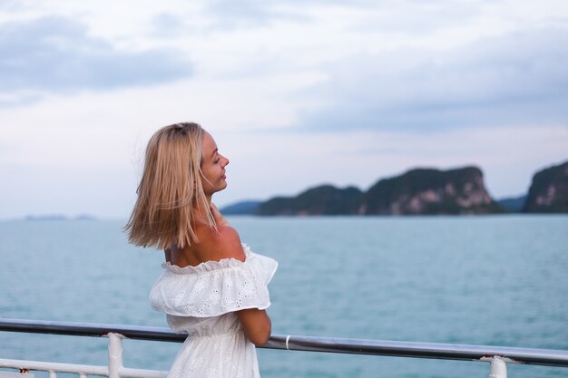 Romantic portrait of woman in white dress sailing on large boat ferry