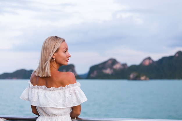 Romantic portrait of woman in white dress sailing on large boat ferry