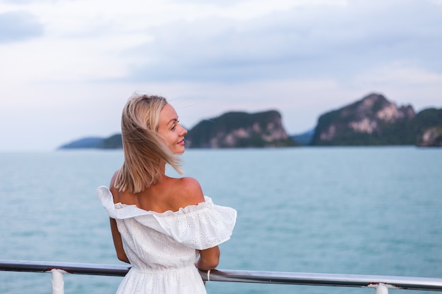 Romantic portrait of woman in white dress sailing on large boat ferry