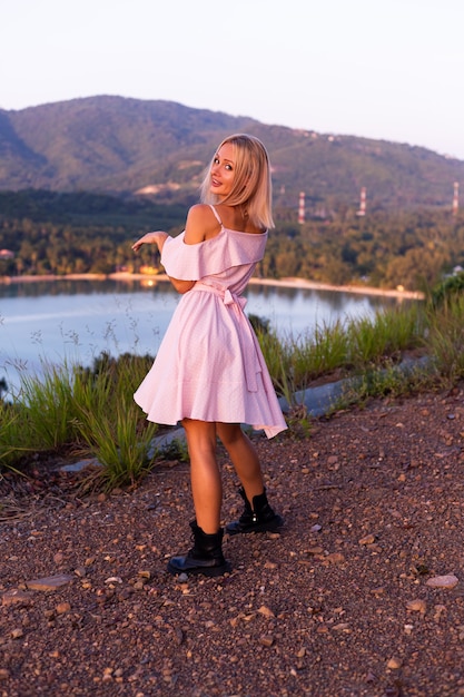 Romantic portrait of young caucasian woman in summer dress enjoying relaxing in park on mountain with amazing tropical sea view Female on vacation travel around Thailand Happy woman at sunset