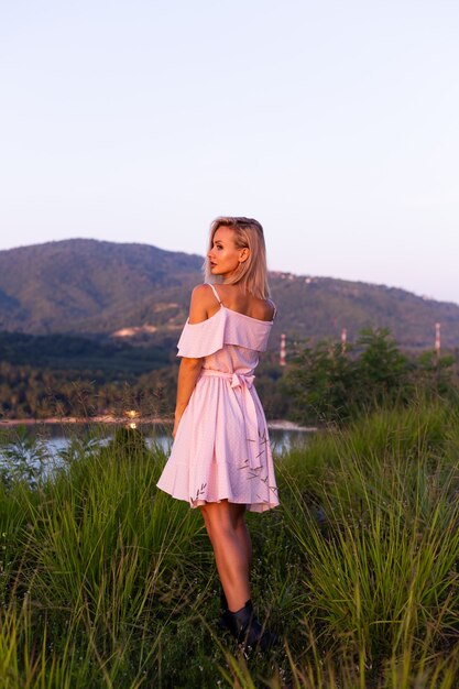 Romantic portrait of young caucasian woman in summer dress enjoying relaxing in park on mountain with amazing tropical sea view Female on vacation travel around Thailand Happy woman at sunset