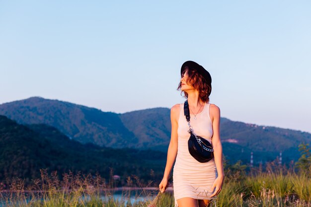 Romantic portrait of young caucasian woman in summer dress enjoying relaxing in park on mountain with amazing tropical sea view Female on vacation travel around Thailand Happy woman at sunset