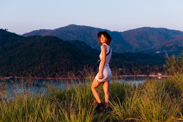 Free photo romantic portrait of young caucasian woman in summer dress enjoying relaxing in park on mountain with amazing tropical sea view female on vacation travel around thailand happy woman at sunset