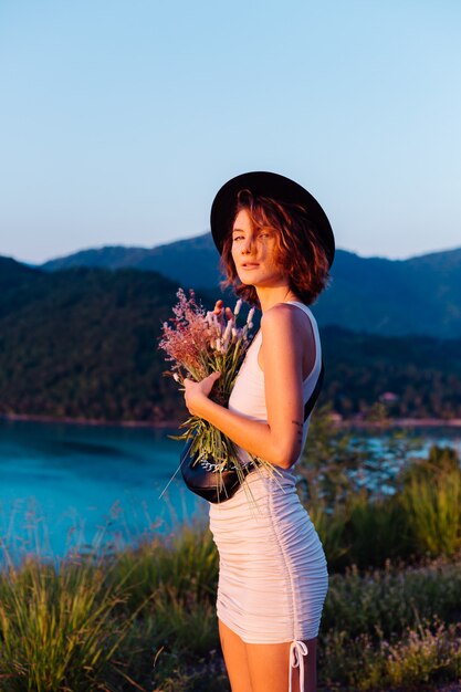 Romantic portrait of young caucasian woman in summer dress enjoying relaxing in park on mountain with amazing tropical sea view