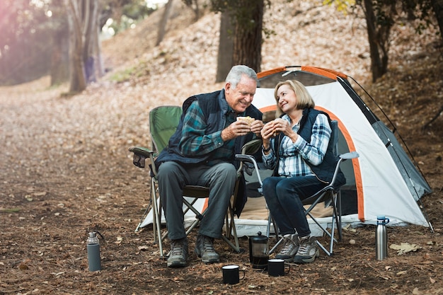キャンプ場でピクニックをしているロマンチックな年配のカップル