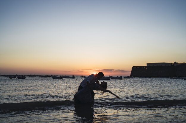 夕日に撮られたビーチでのカップルのシルエットのロマンチックなショット