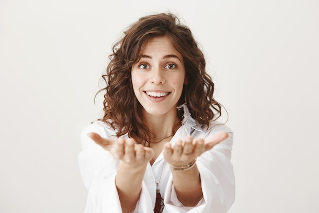 Romantic smiling woman praising you, extend hands as if to give something