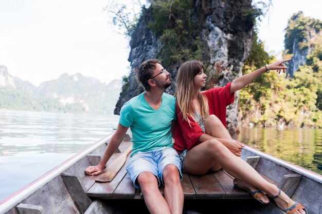 Romantic traveling couple spending vacation time together , sitting on long tail boat, exploring wild nature of Khao Sok national park.