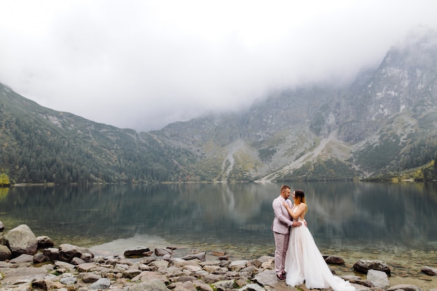 Romantic wedding couple in love standing of the Sea Eye lake in Poland. Tatra mountains.