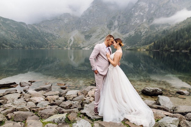 Romantic wedding couple in love standing of the Sea Eye lake in Poland. Tatra mountains.