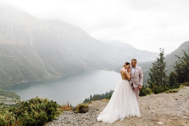Romantic wedding couple in love standing of the Sea Eye lake in Poland. Tatra mountains.