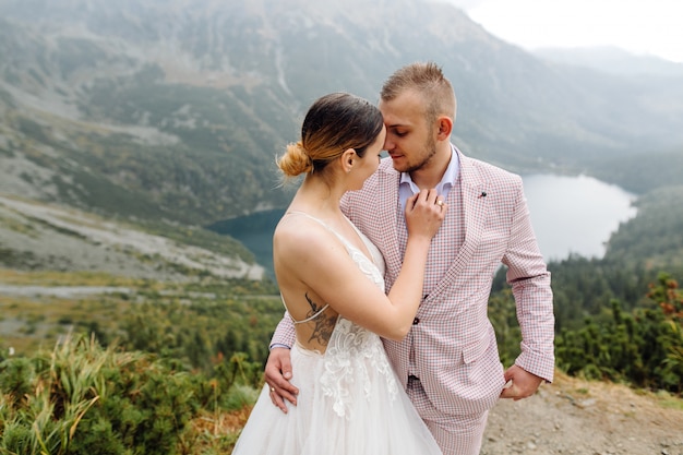 Romantic wedding couple in love standing of the Sea Eye lake in Poland. Tatra mountains.