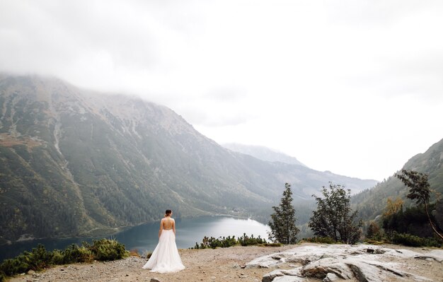 ポーランドのシーアイ湖の愛立っているロマンチックな結婚式のカップル。タトラ山脈。