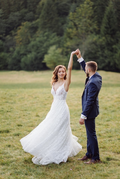 恋にロマンチックな結婚式のカップルは山や森を散歩します