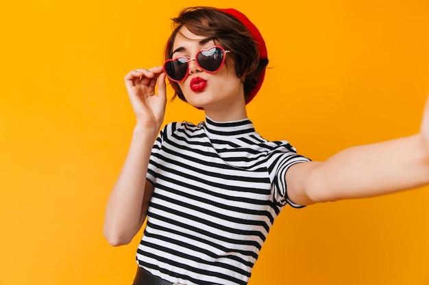 Romantic woman in heart-shaped glasses taking selfie