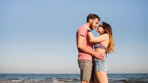ビーチで青い空を背景にロマンチックな若いカップル