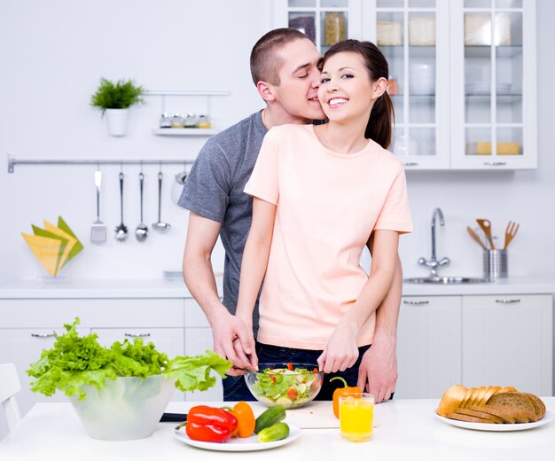 ロマンチックな若いカップルがキッチンで一緒に料理