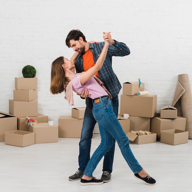 Romantic young couple dancing in front of cardboard boxes