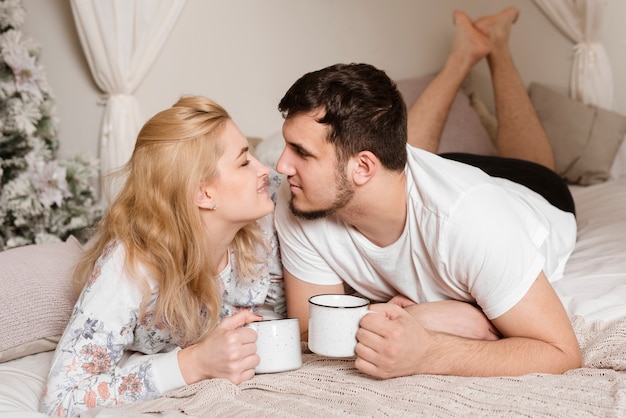 Foto gratuita giovani coppie romantiche che mangiano caffè a letto